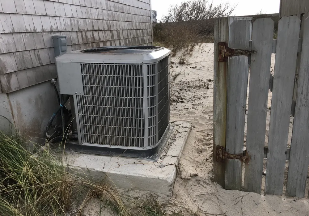 Air conditioning condenser beside a salt-weathered beach house on the Gulf Coast